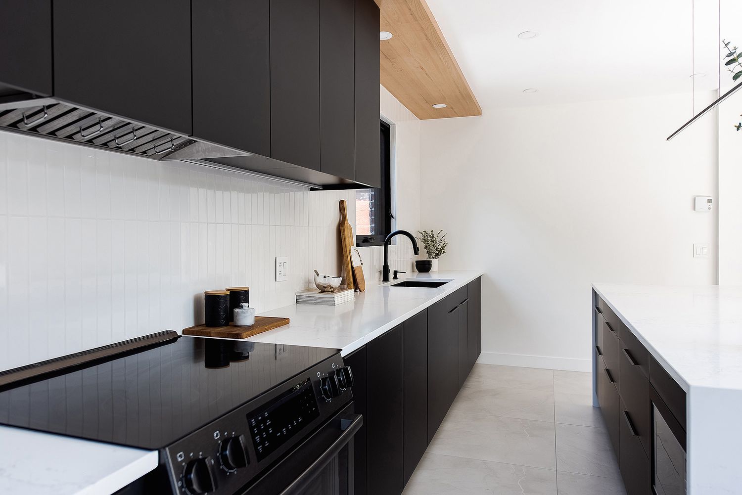 Sleek black kitchen with white countertops featuring built-in appliances and minimal decor.