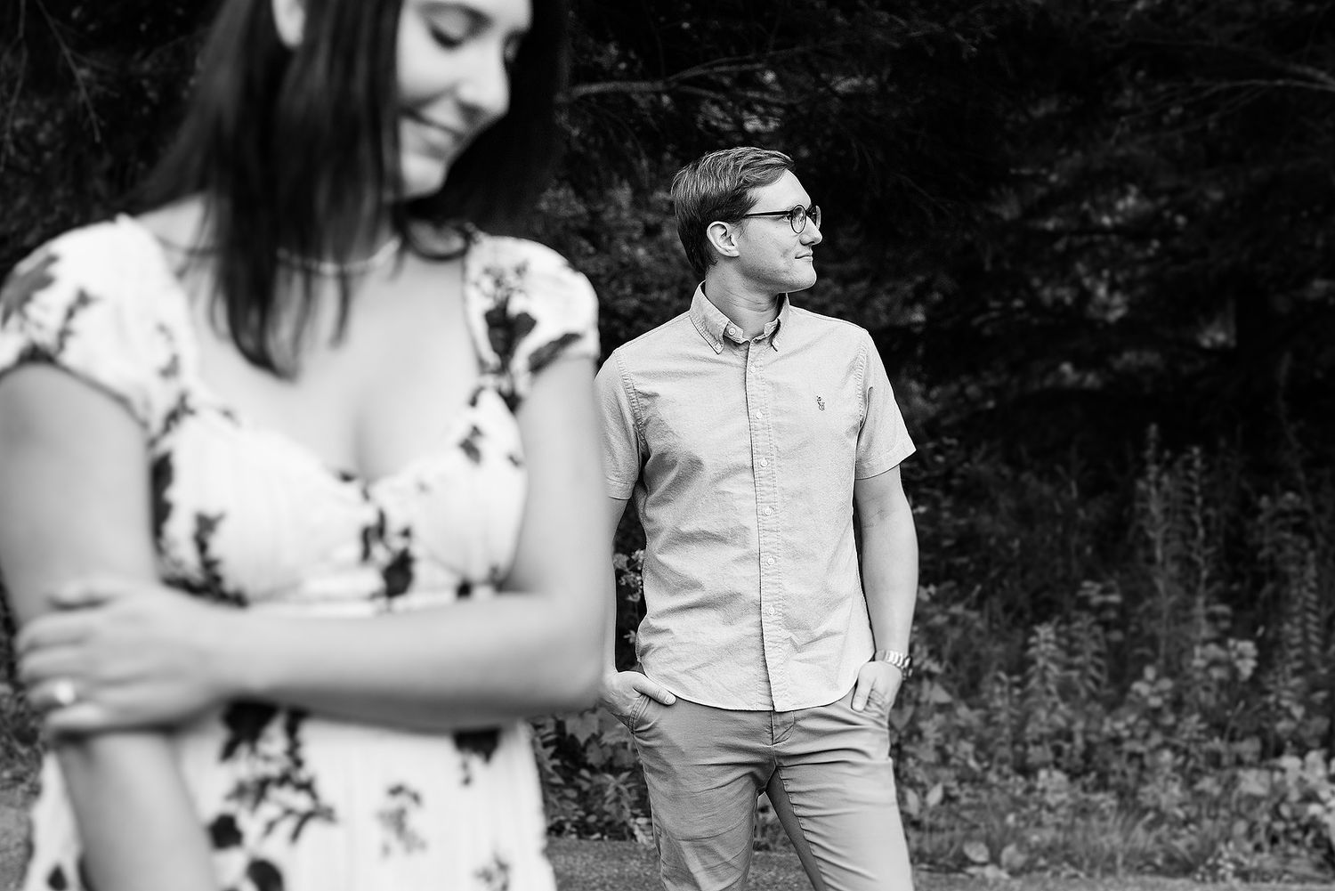 A playful black and white portrait of a couple in a natural outdoor setting.