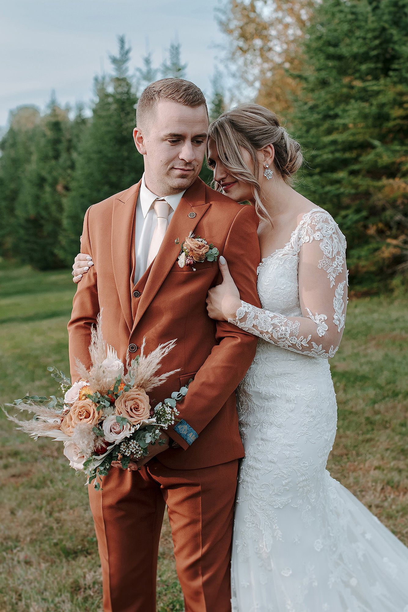 A romantic outdoor wedding photo series featuring a couple in a rust-colored suit and lace wedding dress with autumn florals.