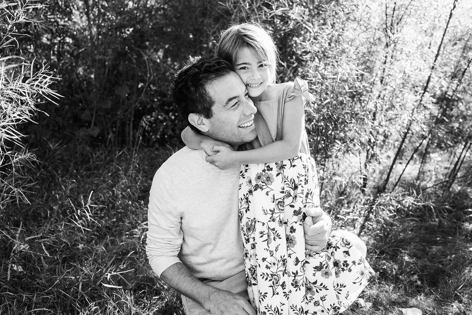 Black and white family portrait series showing tender moments between parents and children in an outdoor setting.