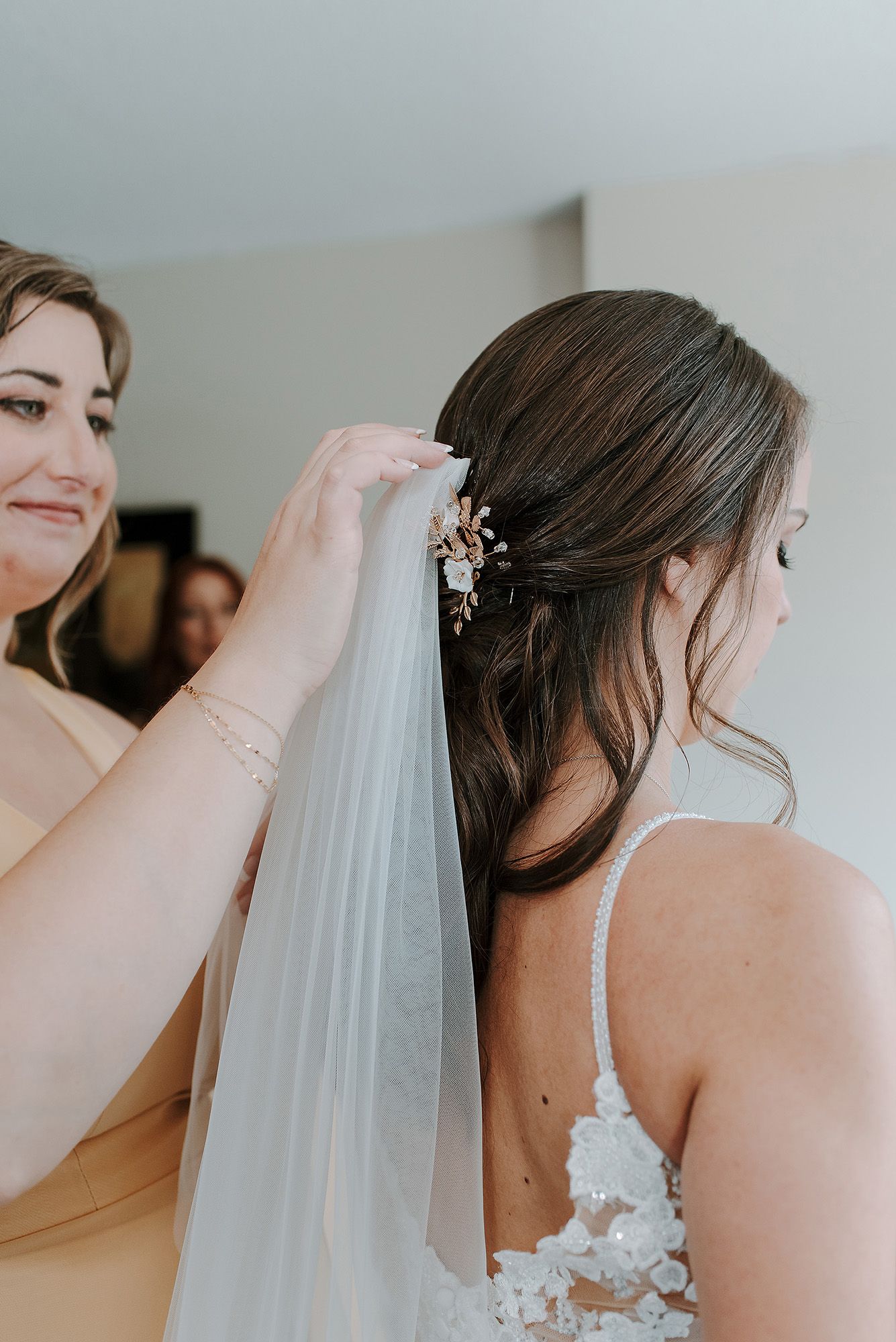 A wedding veil is delicately pinned into an elegant updo hairstyle during bridal preparations.
