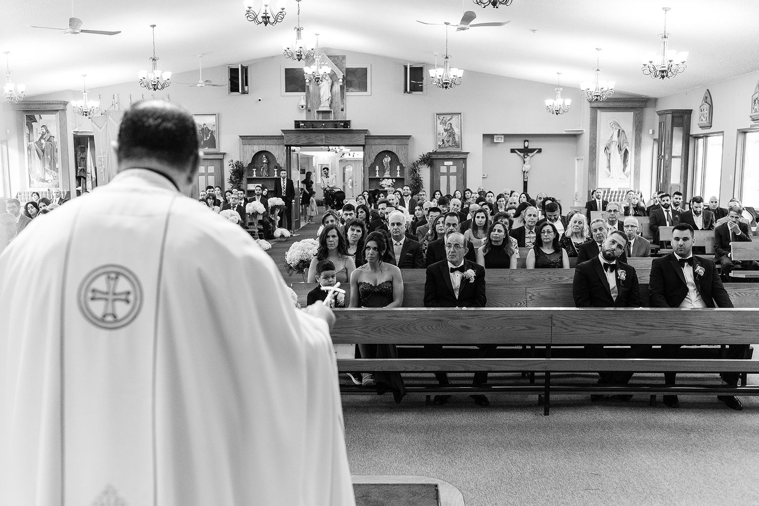 Black and white panoramic view of a church interior with pews filled with people during a religious service.