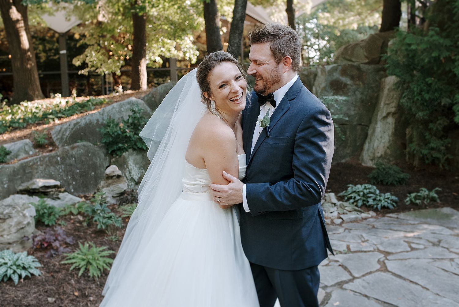 A bride and groom share intimate moments during their wedding photoshoot in a lush garden setting.