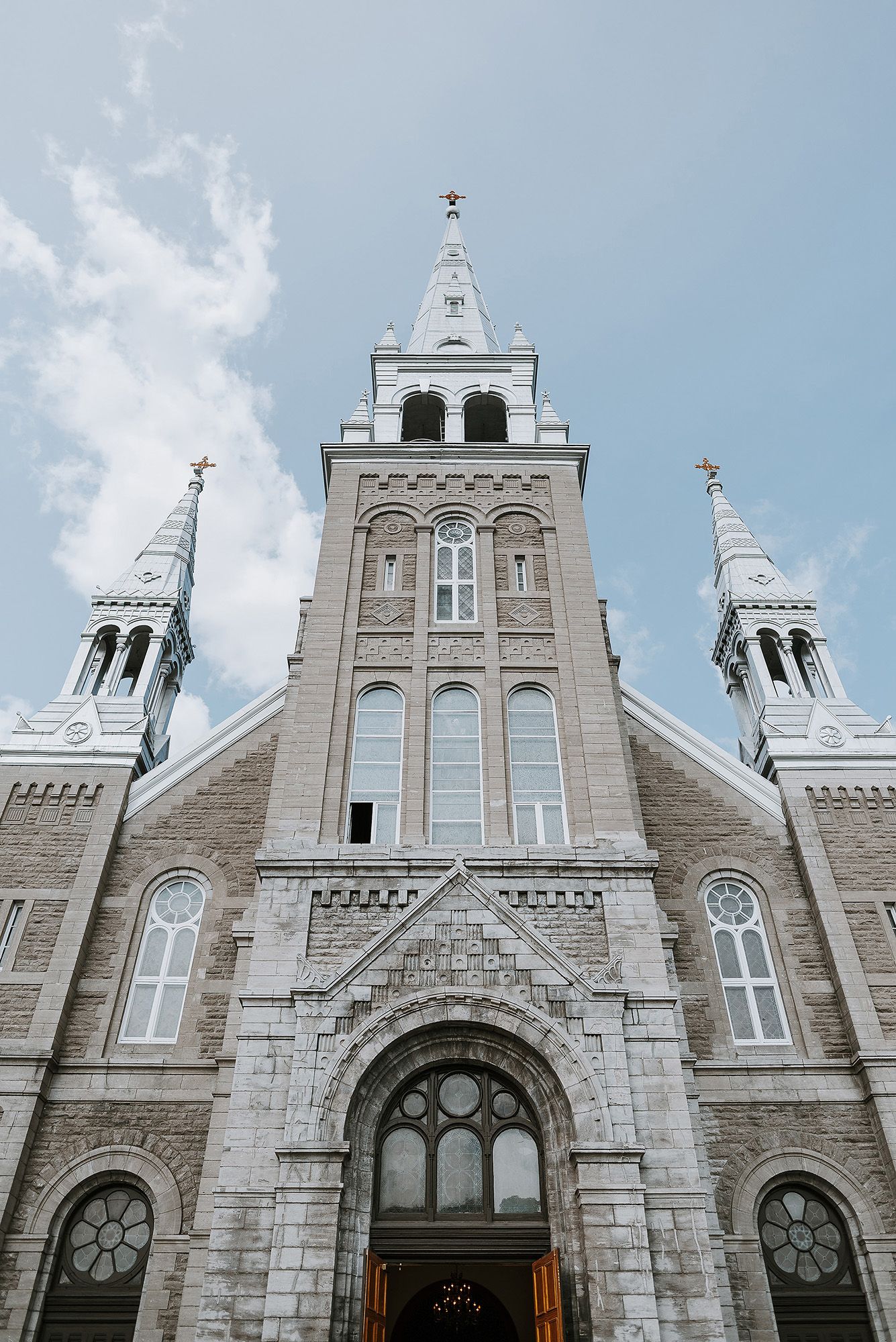 Majestic stone church with Gothic architecture and multiple spires against a blue sky.