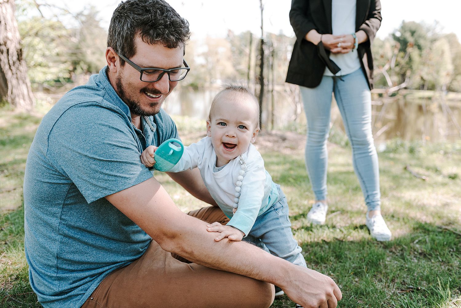 Family enjoying a playful moment together on grass during outdoor photoshoot.