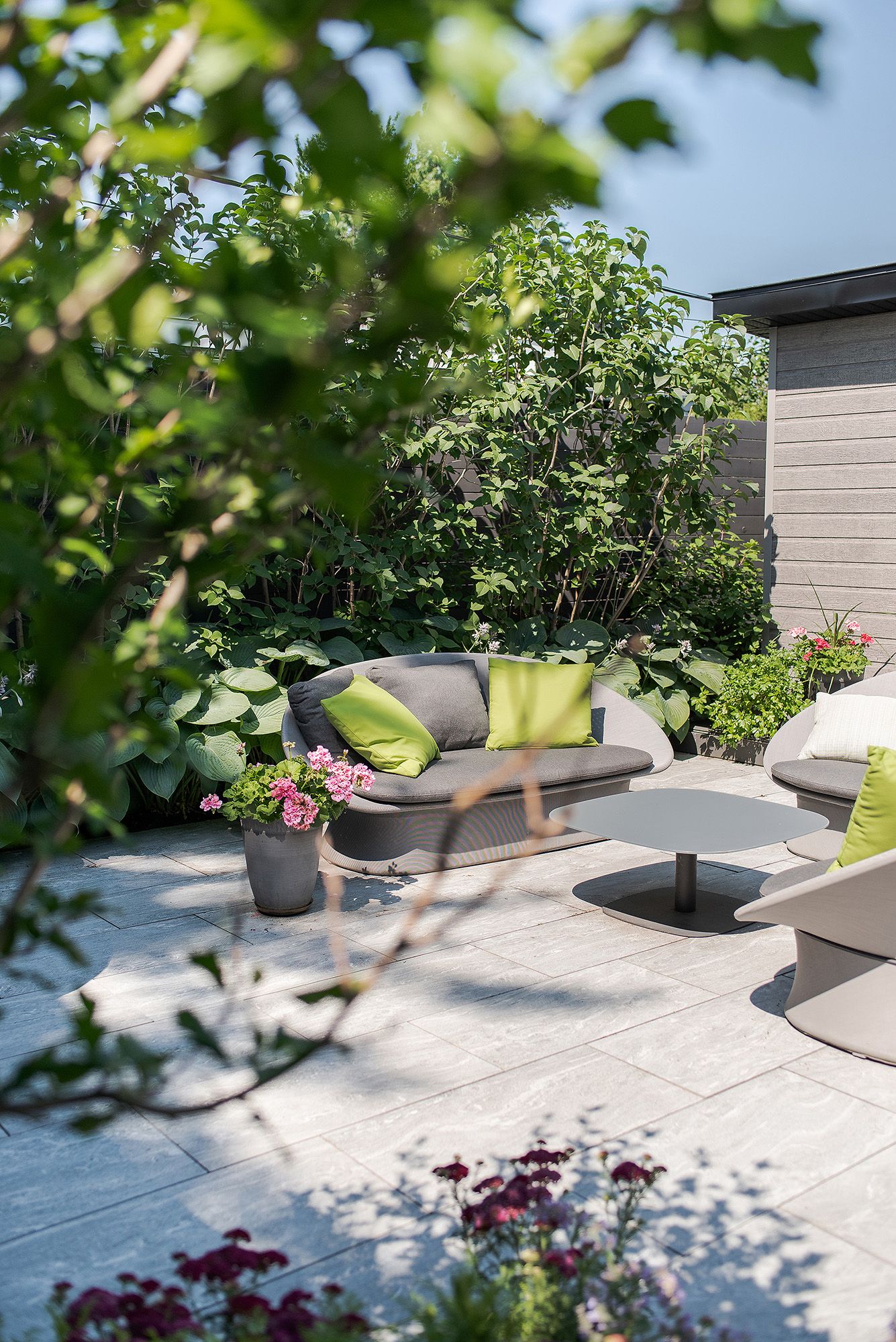 Sunlit outdoor terrace with modern planters and greenery creating a serene garden atmosphere on a patio space.
