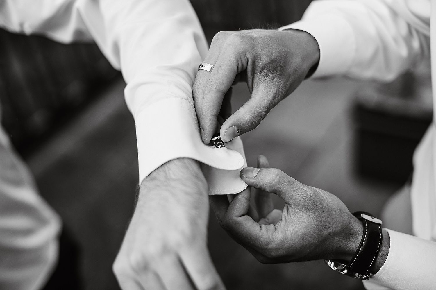Close-up black and white shots of hands and wedding rings during an intimate ceremony moment.