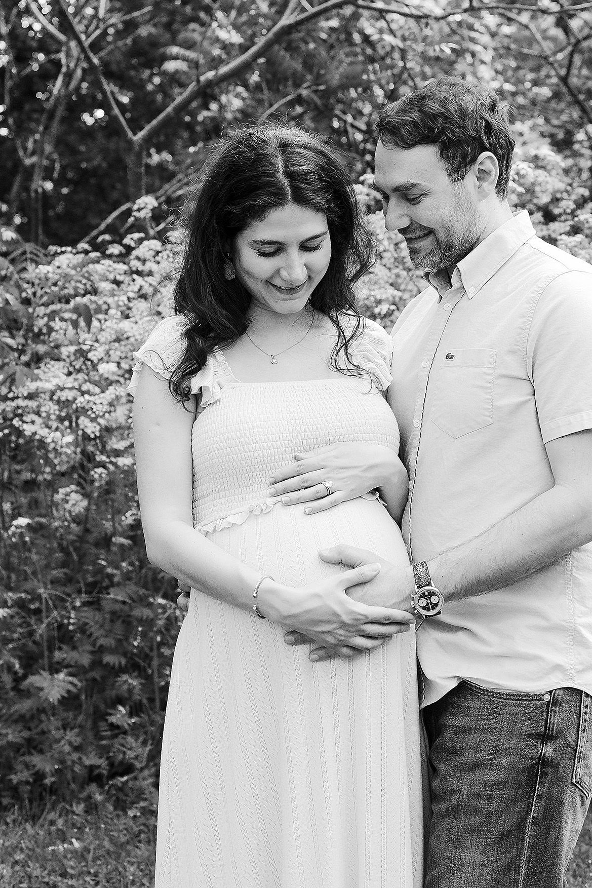 A couple in white clothing share tender moments outdoors in a series of black and white photographs.