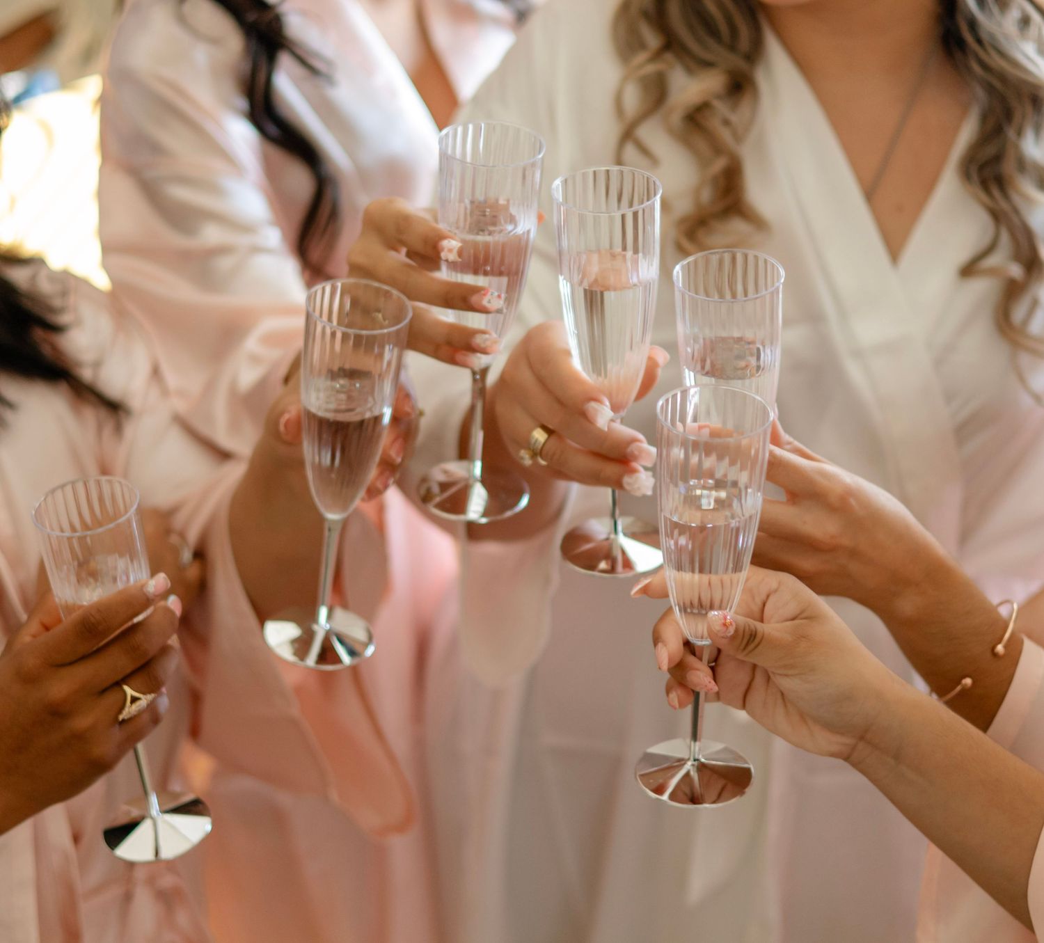 Hands holding champagne glasses in a celebratory toast moment.