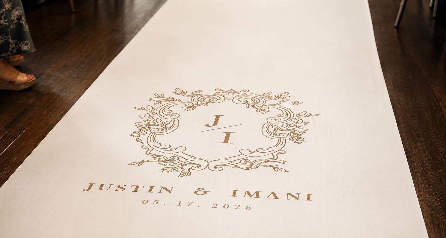 Custom white wedding aisle runner with ornate gold monogram crest reading Justin & Imani, dated 08.17.2020.
