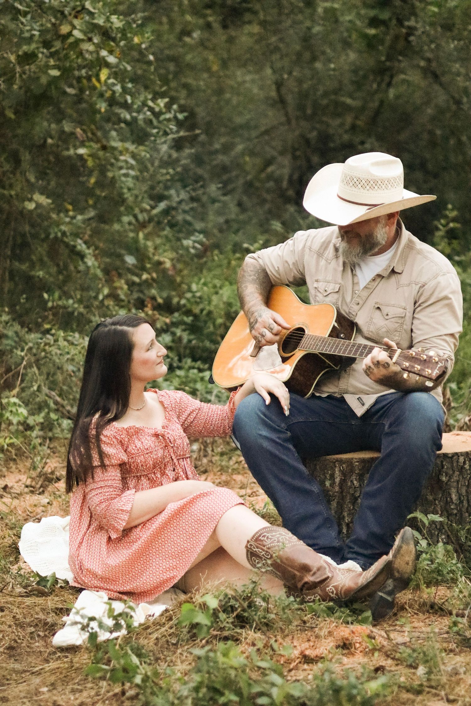 Country couple relaxing on grass with acoustic guitar during outdoor photoshoot.