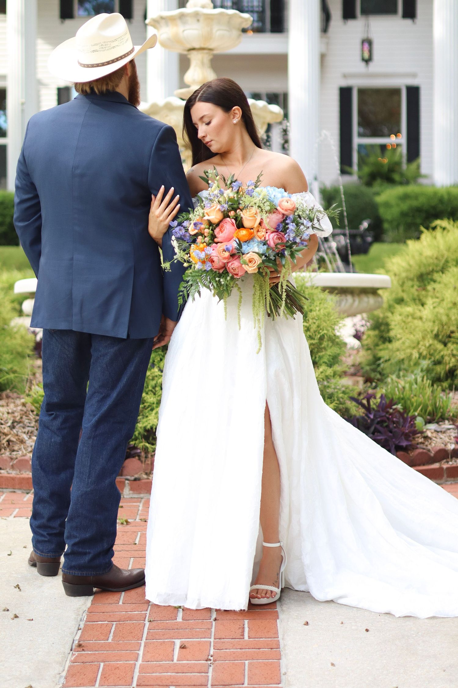 Wedding portraits showing couple with colorful bouquet against white colonial architecture.
