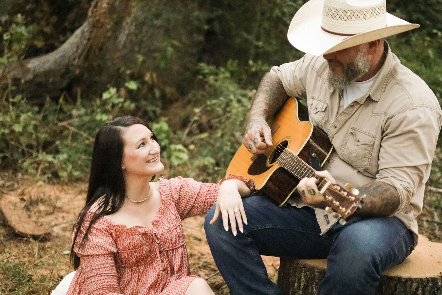 A couple shares intimate moments outdoors with an acoustic guitar.