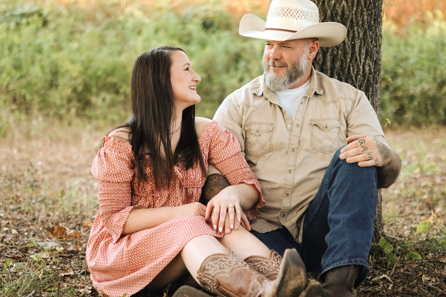 A couple in casual attire shares tender moments during an outdoor engagement photo session.