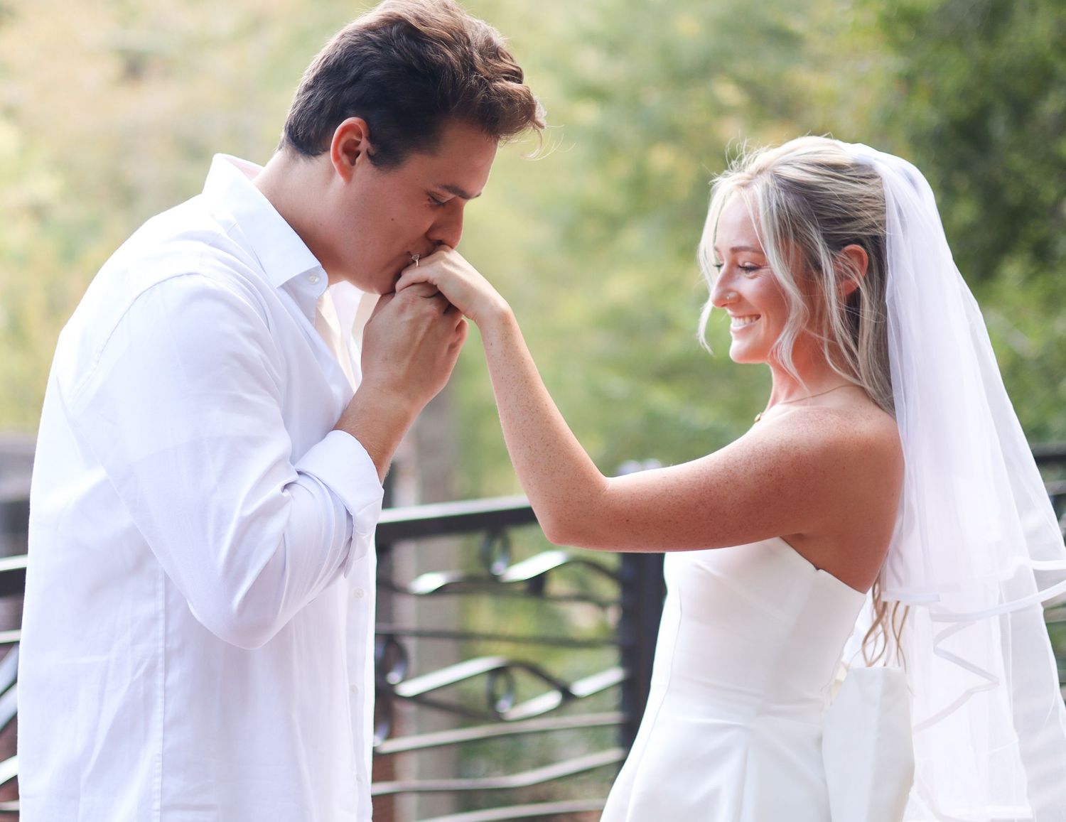 A tender moment between newlyweds on their wedding day with white attire and natural lighting.