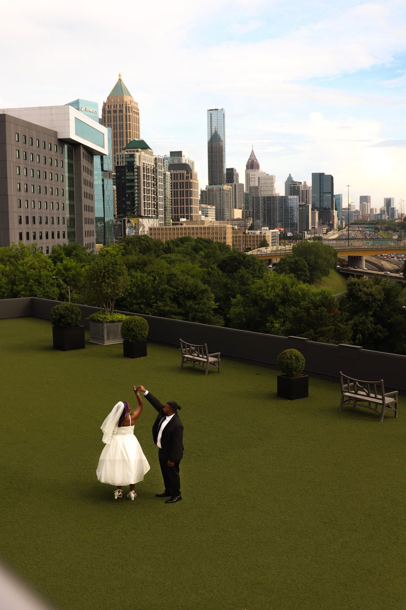 Bride and groom dancing on a rooftop garden with the Atlanta city skyline in the background.
