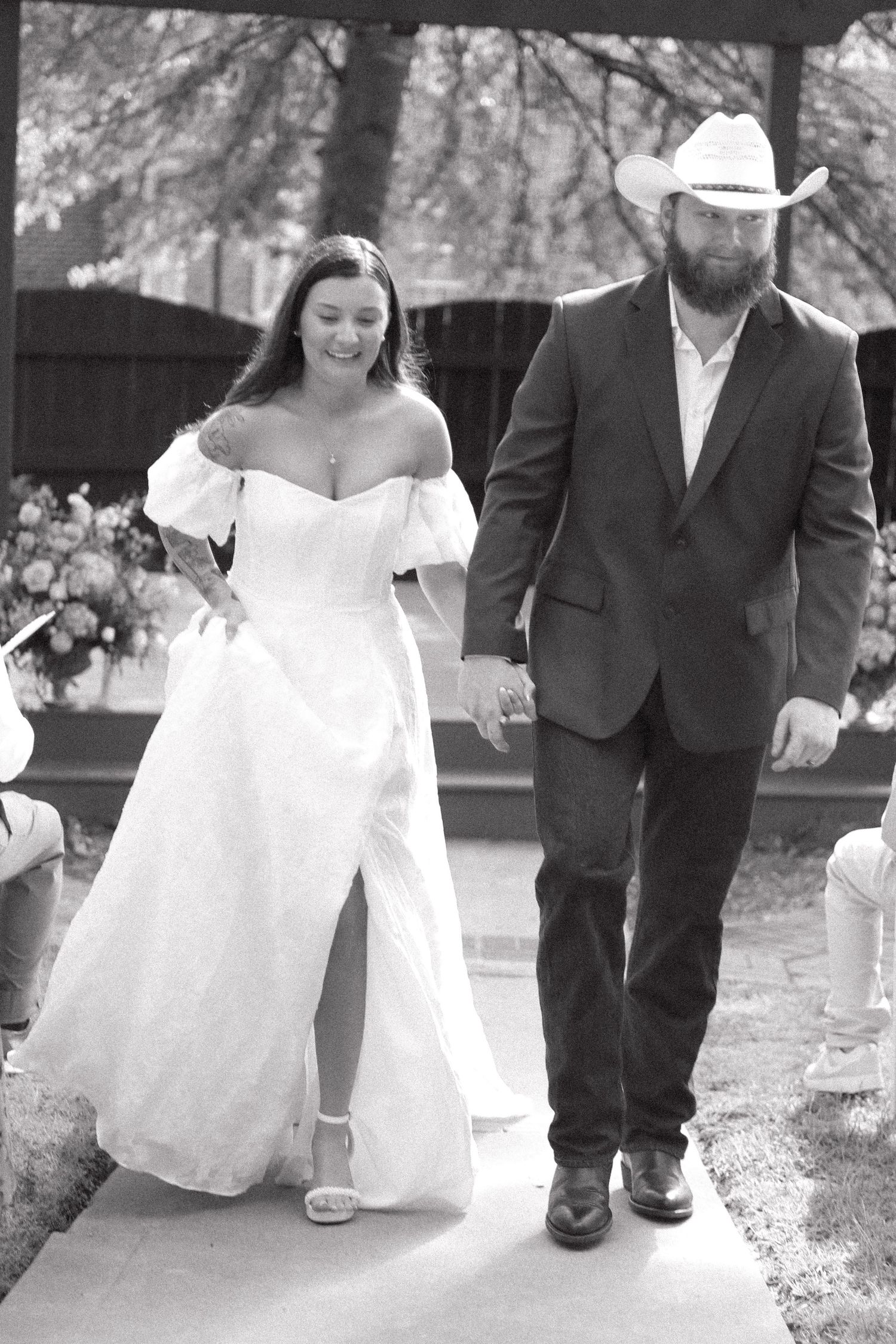Black and white wedding photos showing close-up details of a bride and groom walking together.