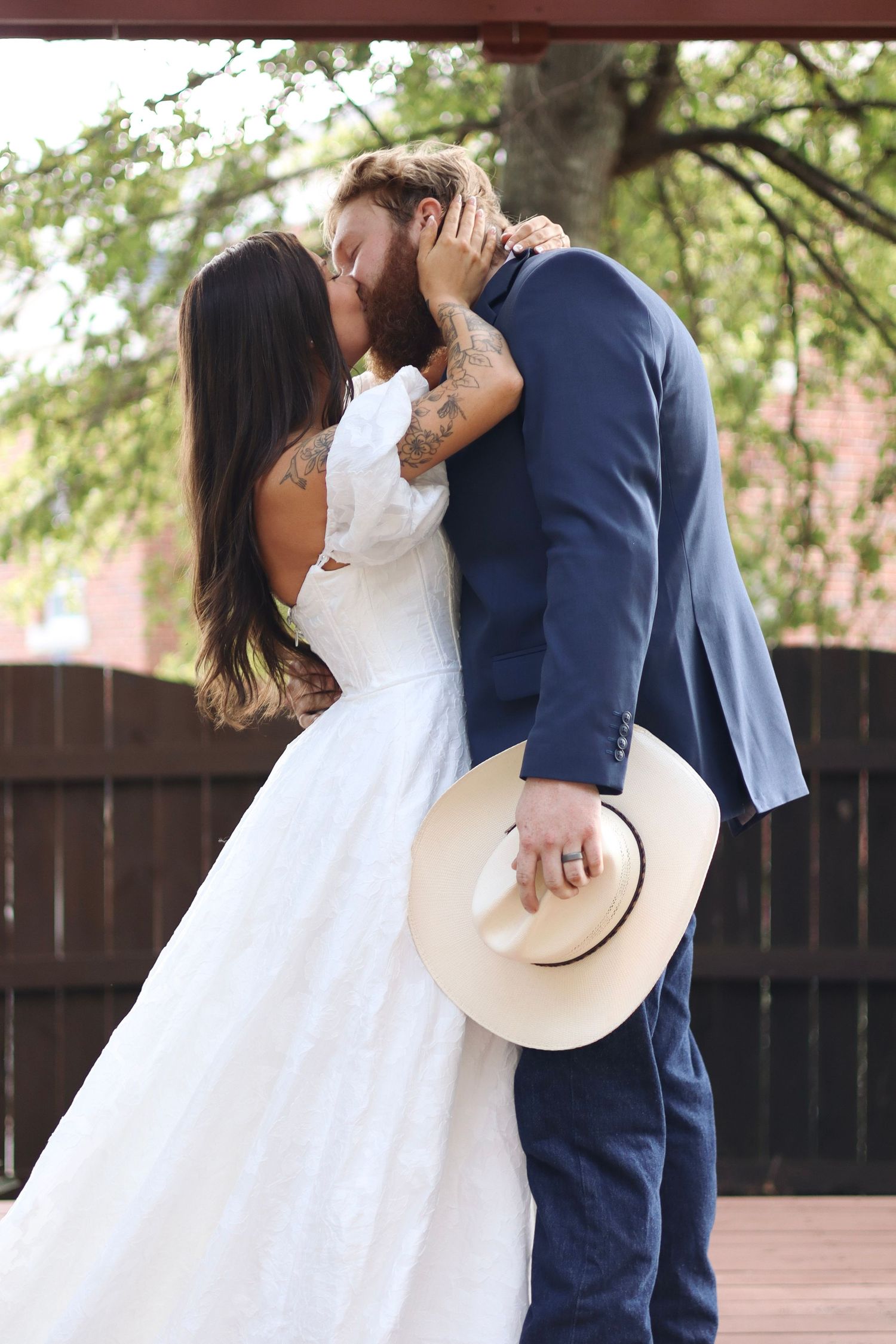 Romantic wedding couple sharing intimate moment on wooden deck.