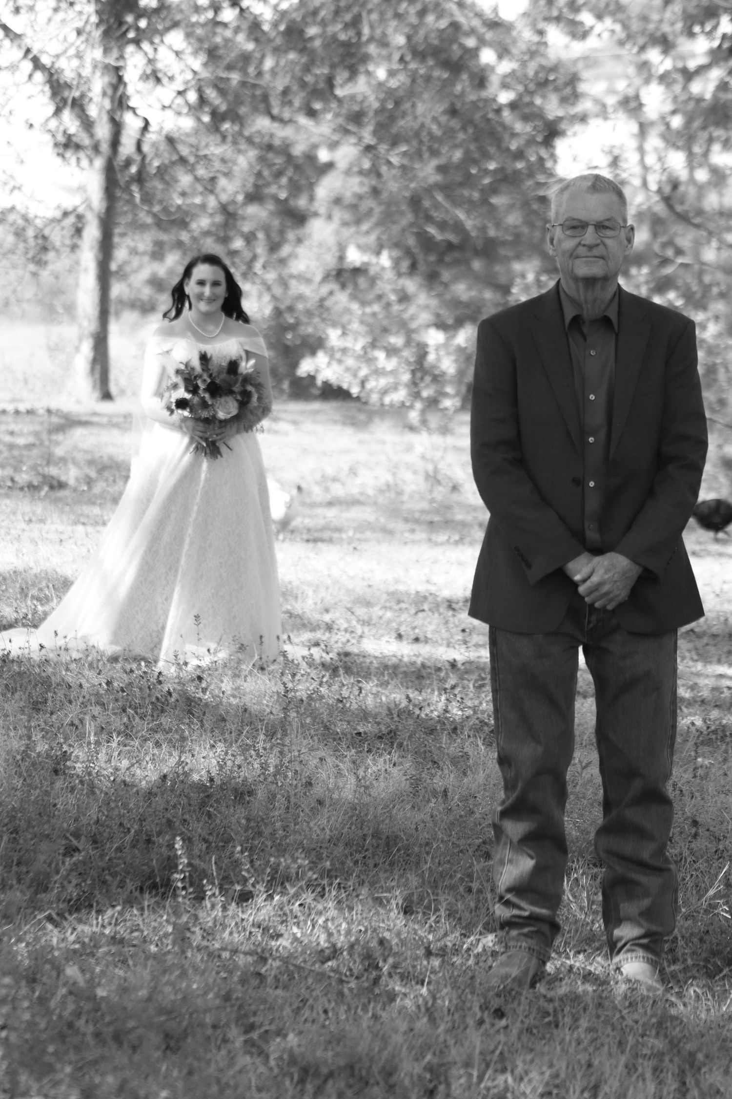 Black and white wedding portrait in a rustic outdoor setting.