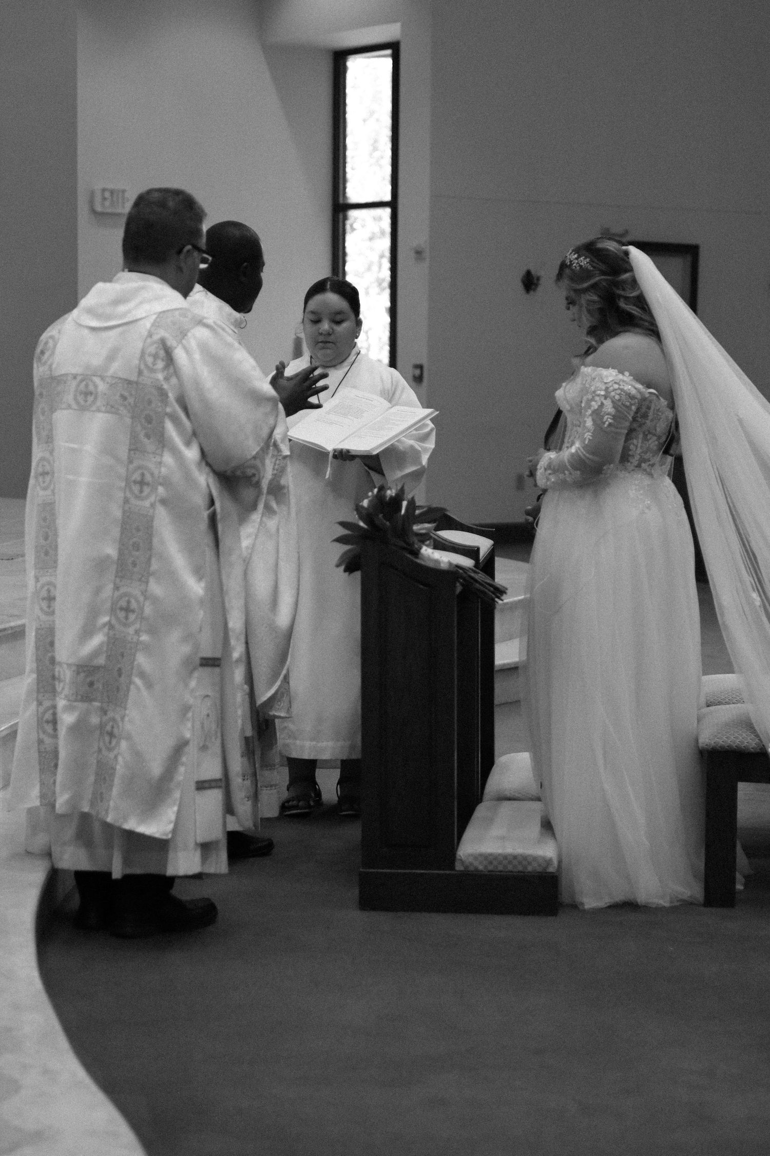 Black and white photo of wedding preparation with flowing white dresses visible.