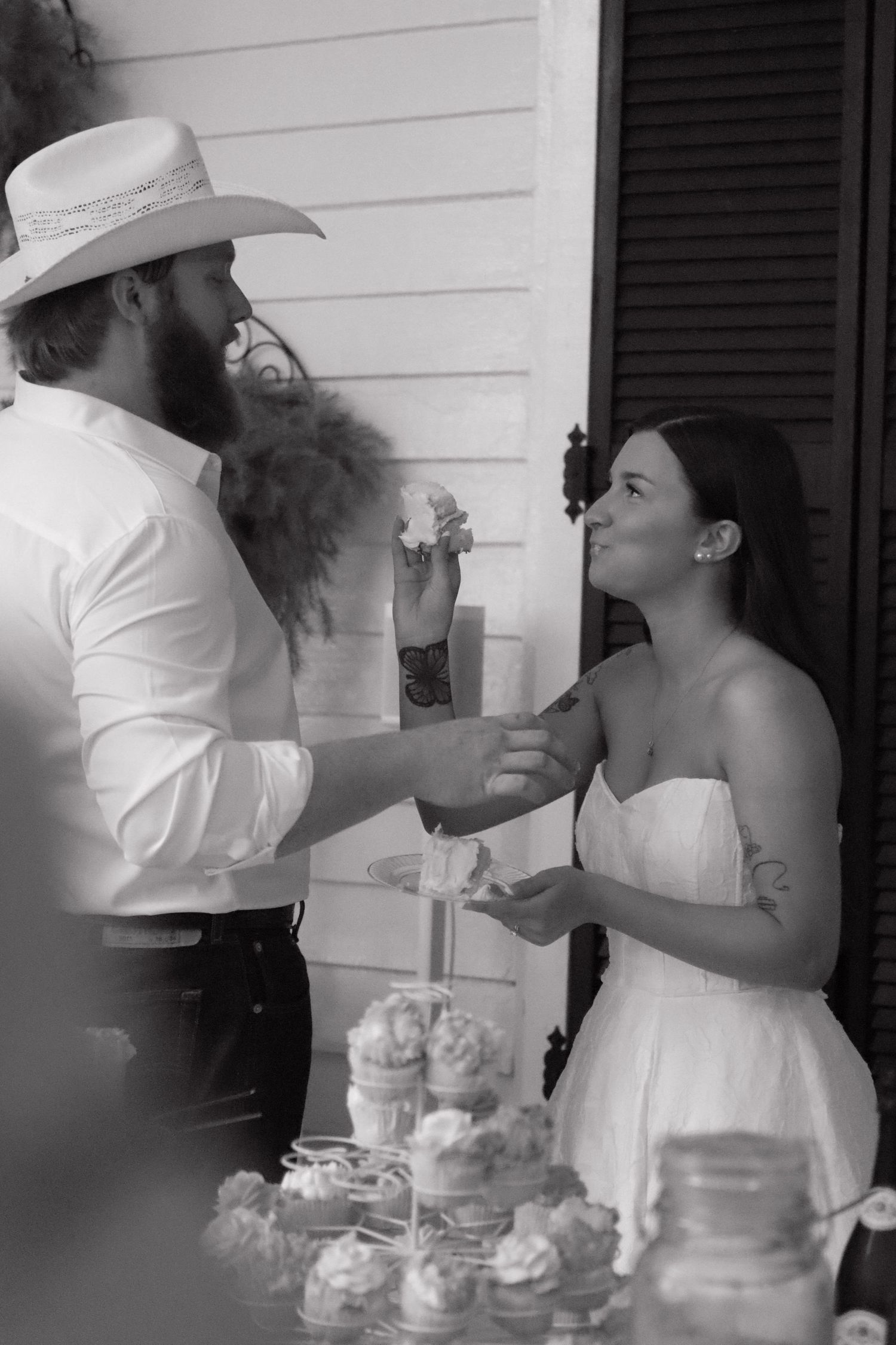 Black and white photos of wedding cake cutting sequence with rustic decor.