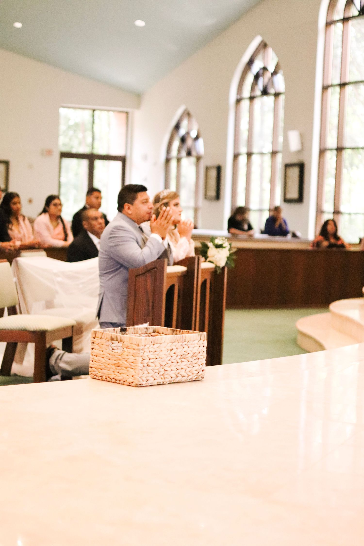 Church interior with arched windows and pews during daytime ceremony.