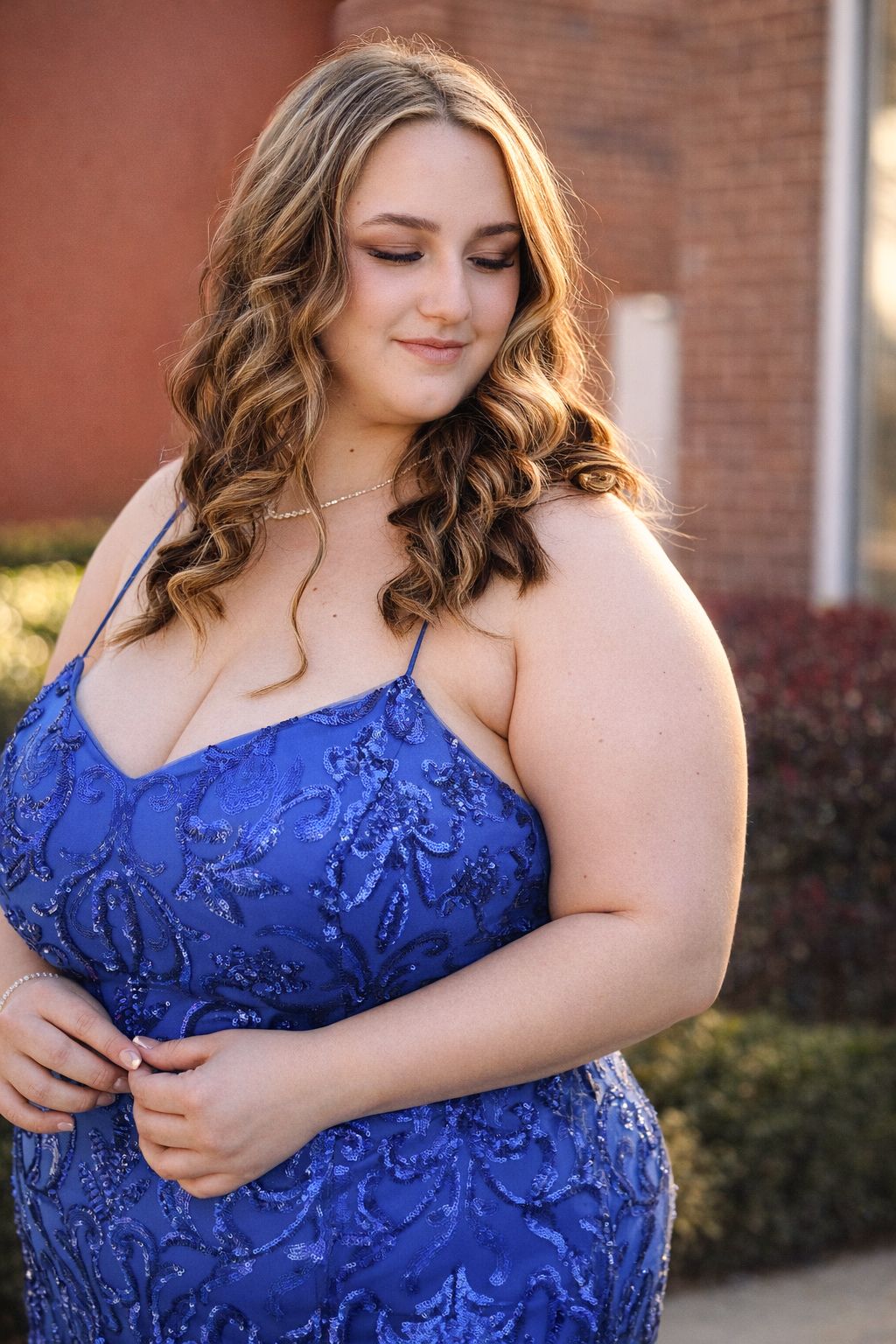 Close-up detail shots of a royal blue lace formal dress against a brick background.