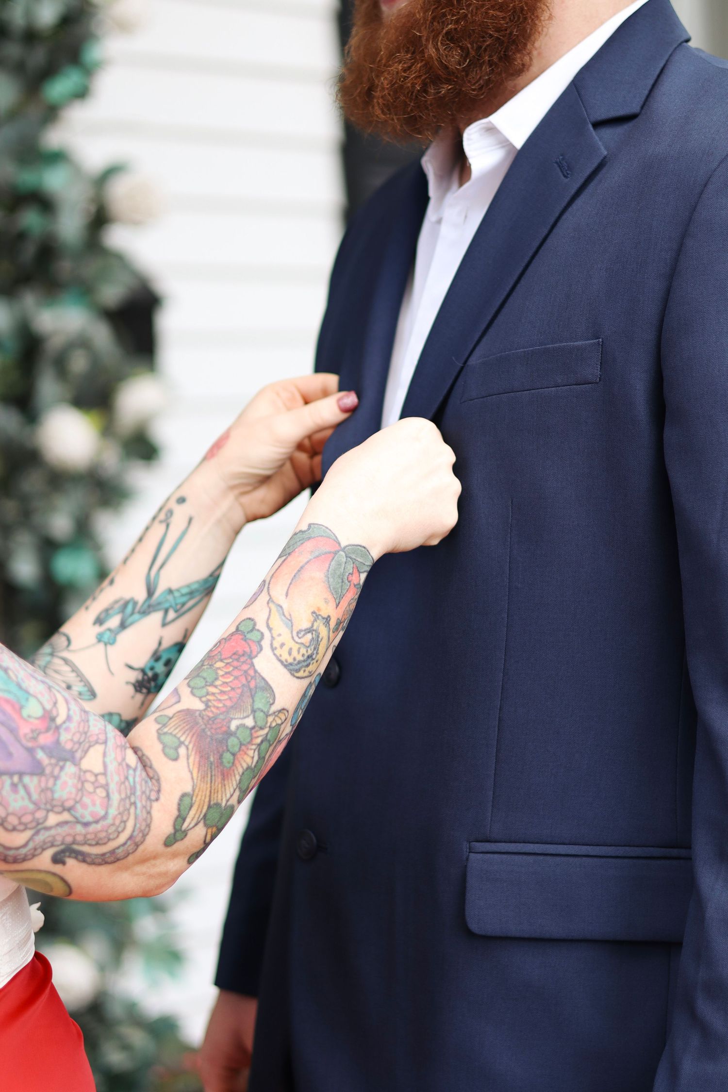 Close-up shots of colorful tattoo sleeve art contrasting with a navy blue suit jacket.