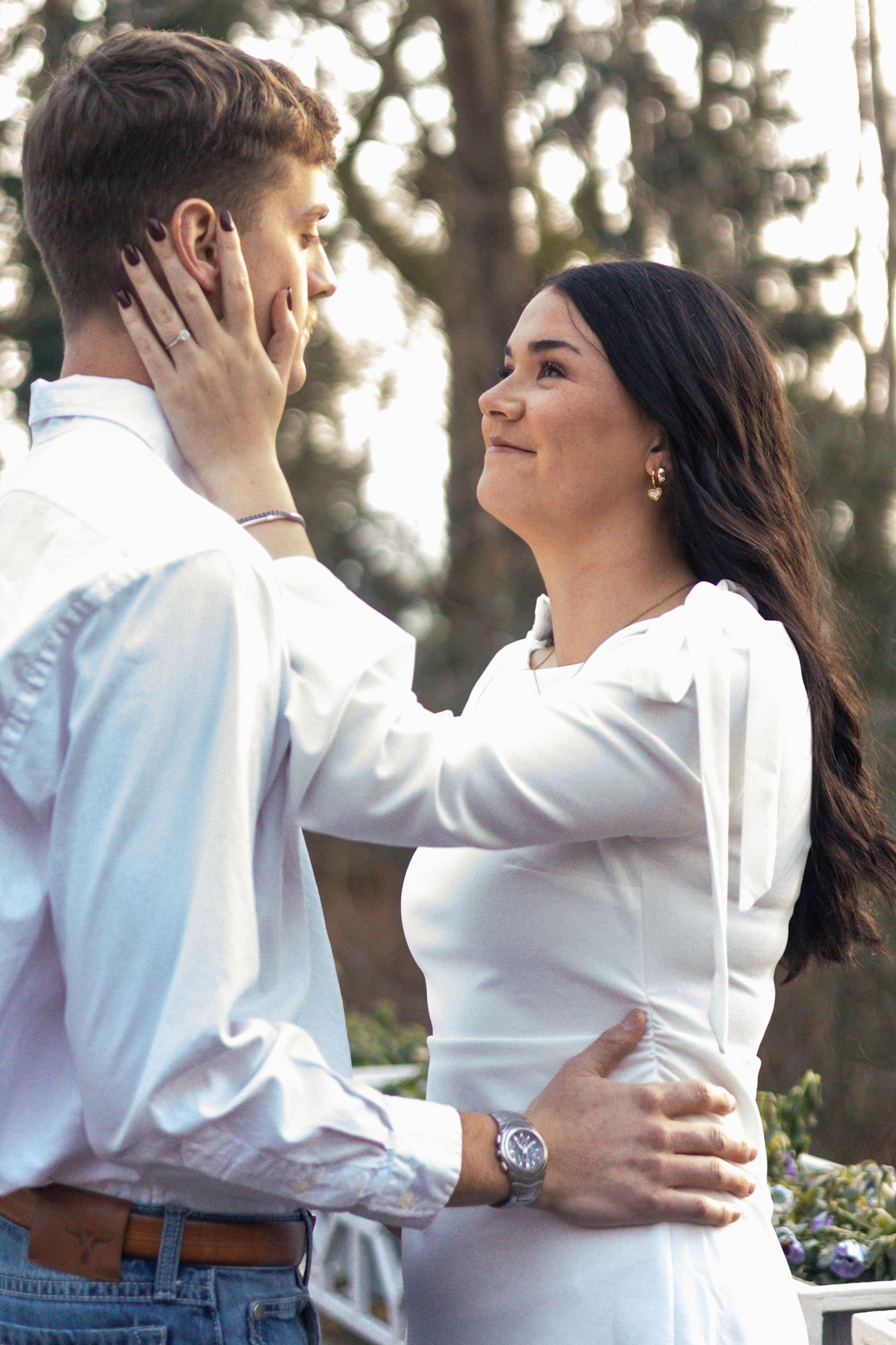 A couple in white shirts embraces outdoors in a romantic sequence of candid moments.