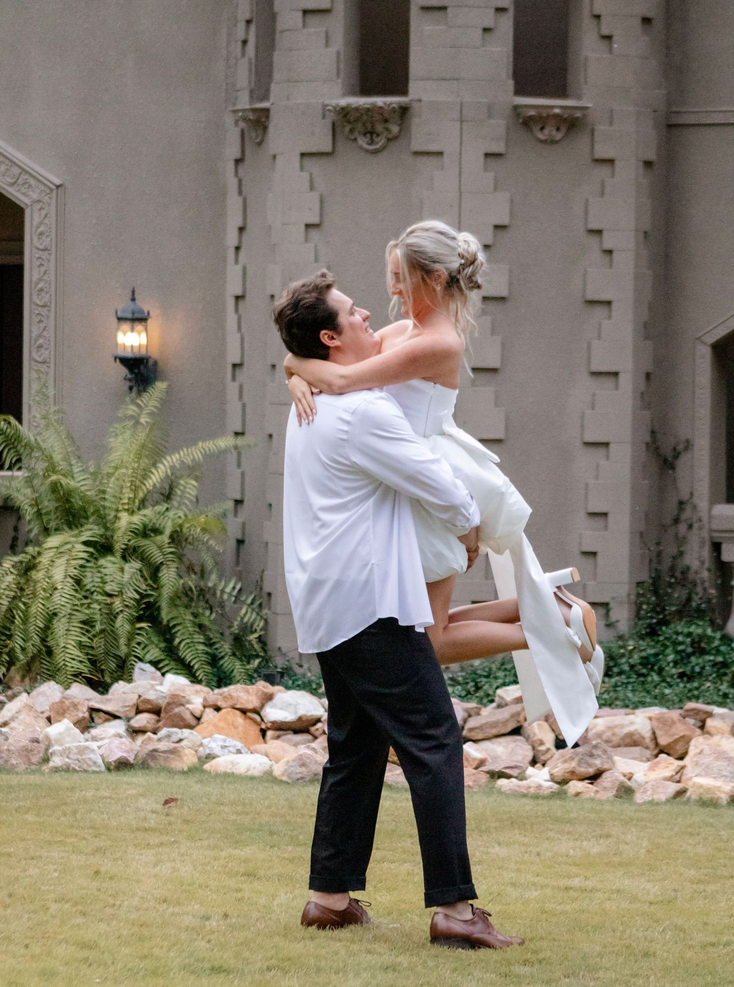 A sequence of dramatic dance dips performed outdoors on a lawn against a stone wall.