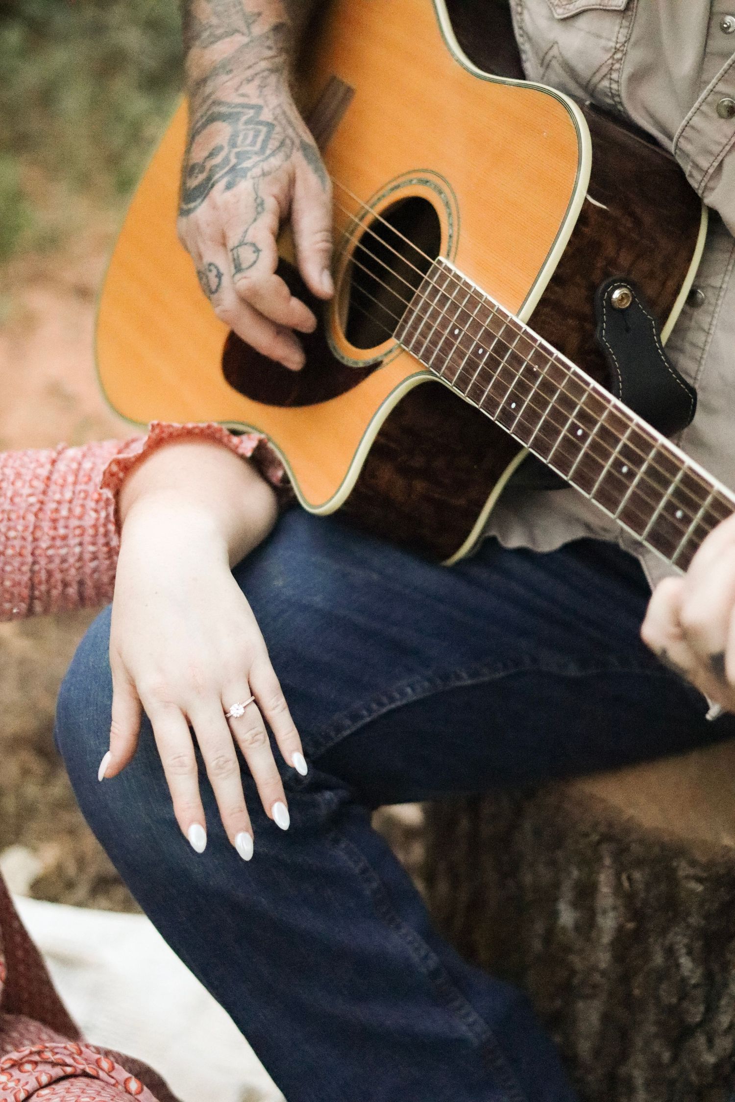 Close-up details of hands and an acoustic guitar during an outdoor photoshoot.