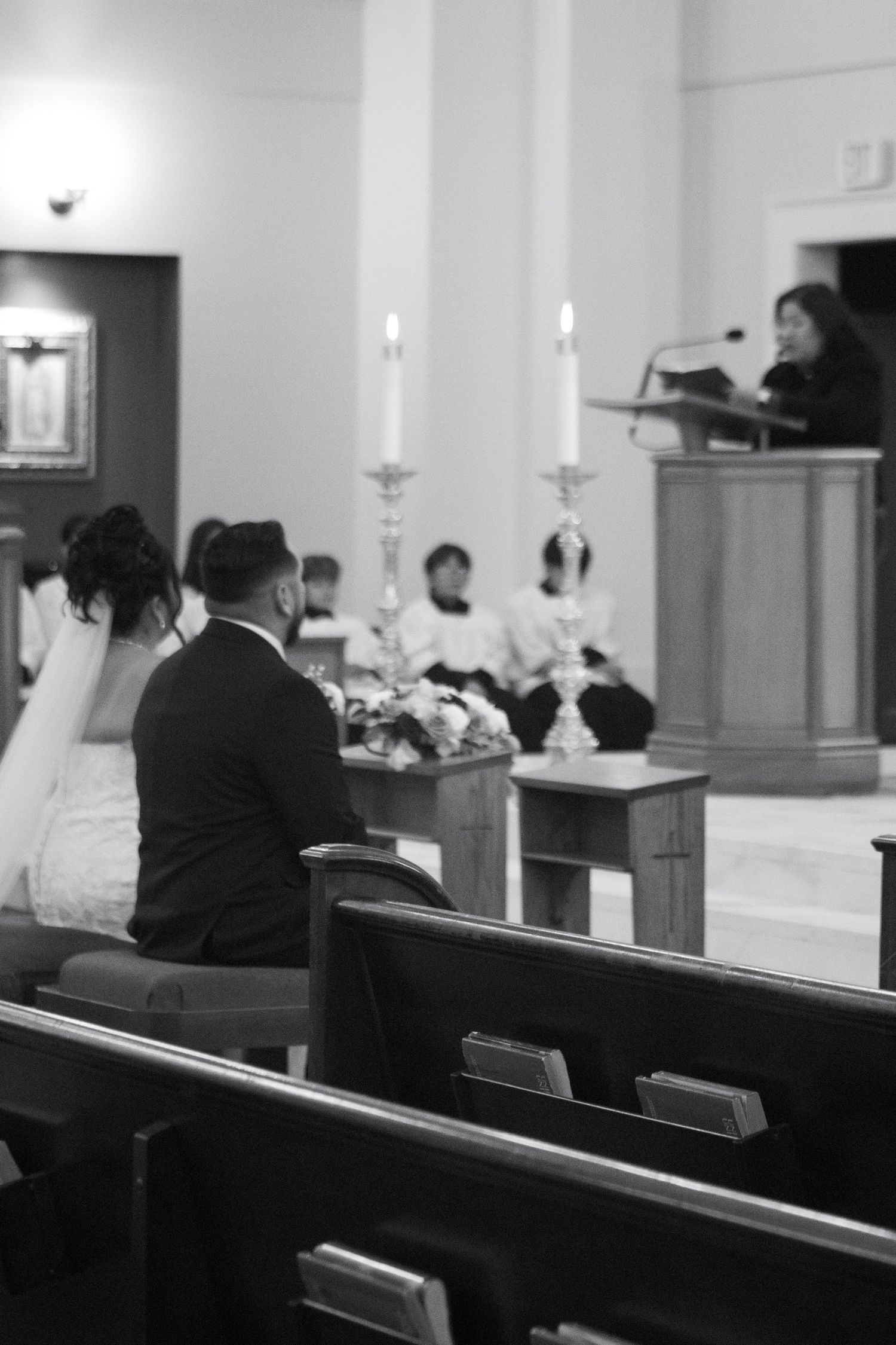 Black and white photo showing people sitting in church pews during a candlelit service.