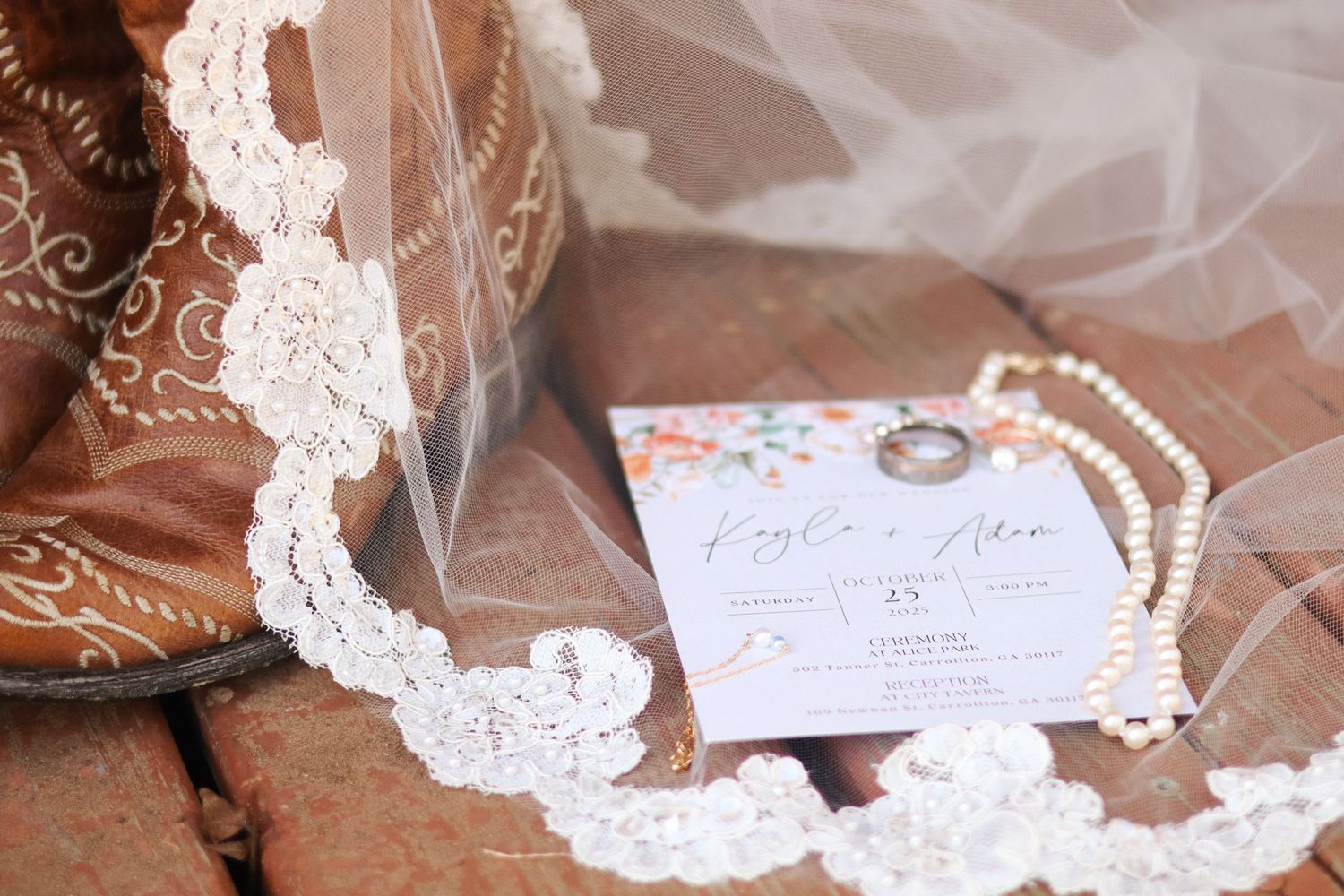 Wedding details featuring lace veil, invitation cards and decorative elements on brick surface.