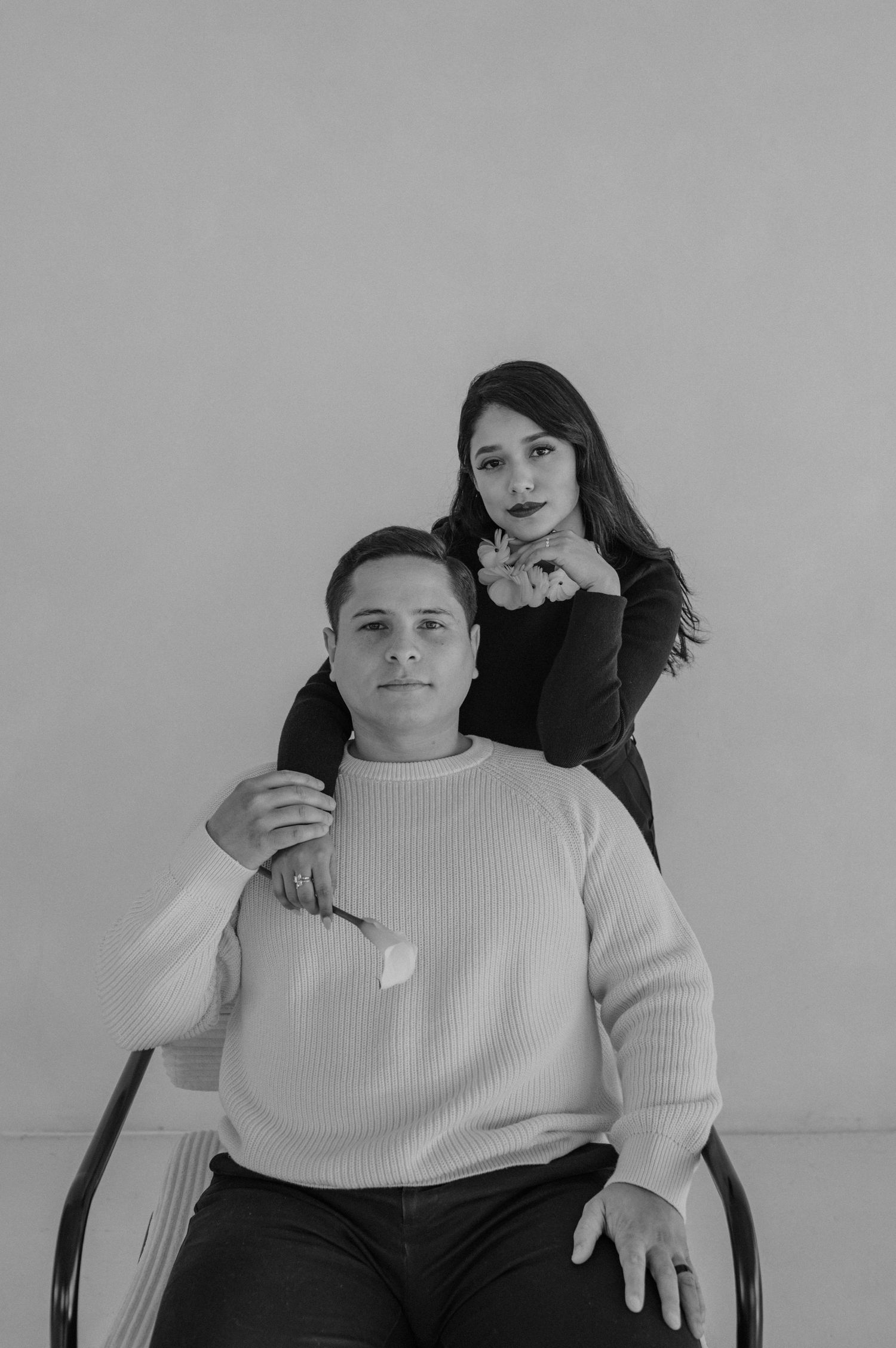 Black-and-white portrait of a man seated and a woman standing behind him — professional studio duo image.