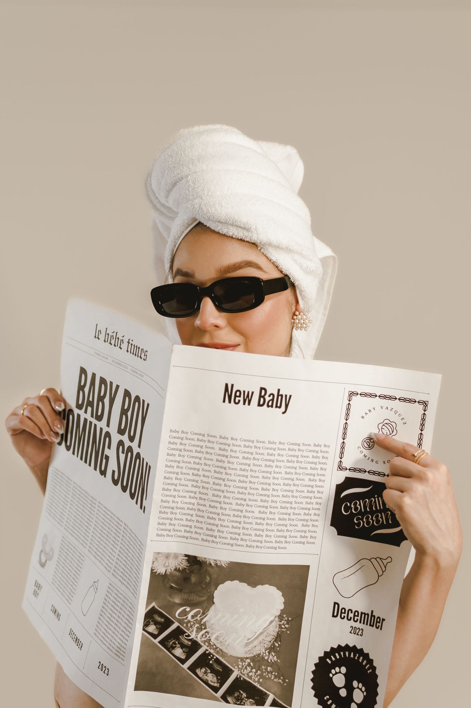 Pregnant woman with towel on head reading newspaper announcing baby boy coming soon in December.