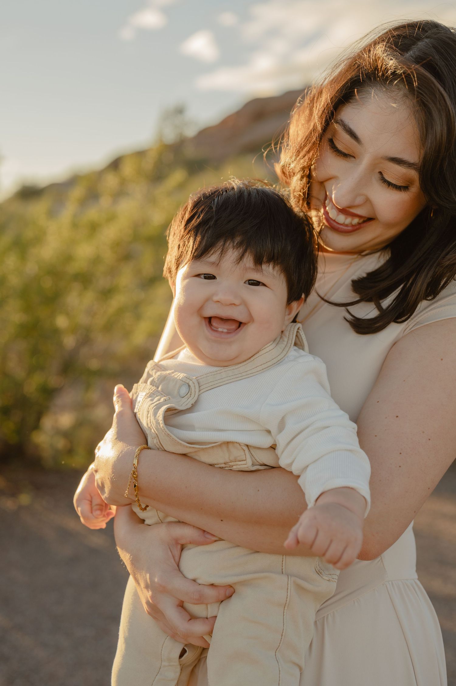 A mother laughs with her baby boy in the warm desert sunset light at Papago Park, Phoenix, AZ.