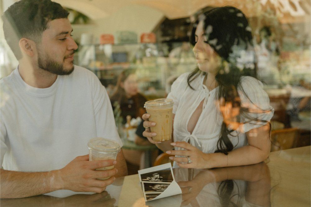 Couple sharing iced coffee at Sophia's Brunch Counter with a sonogram resting on the table between them