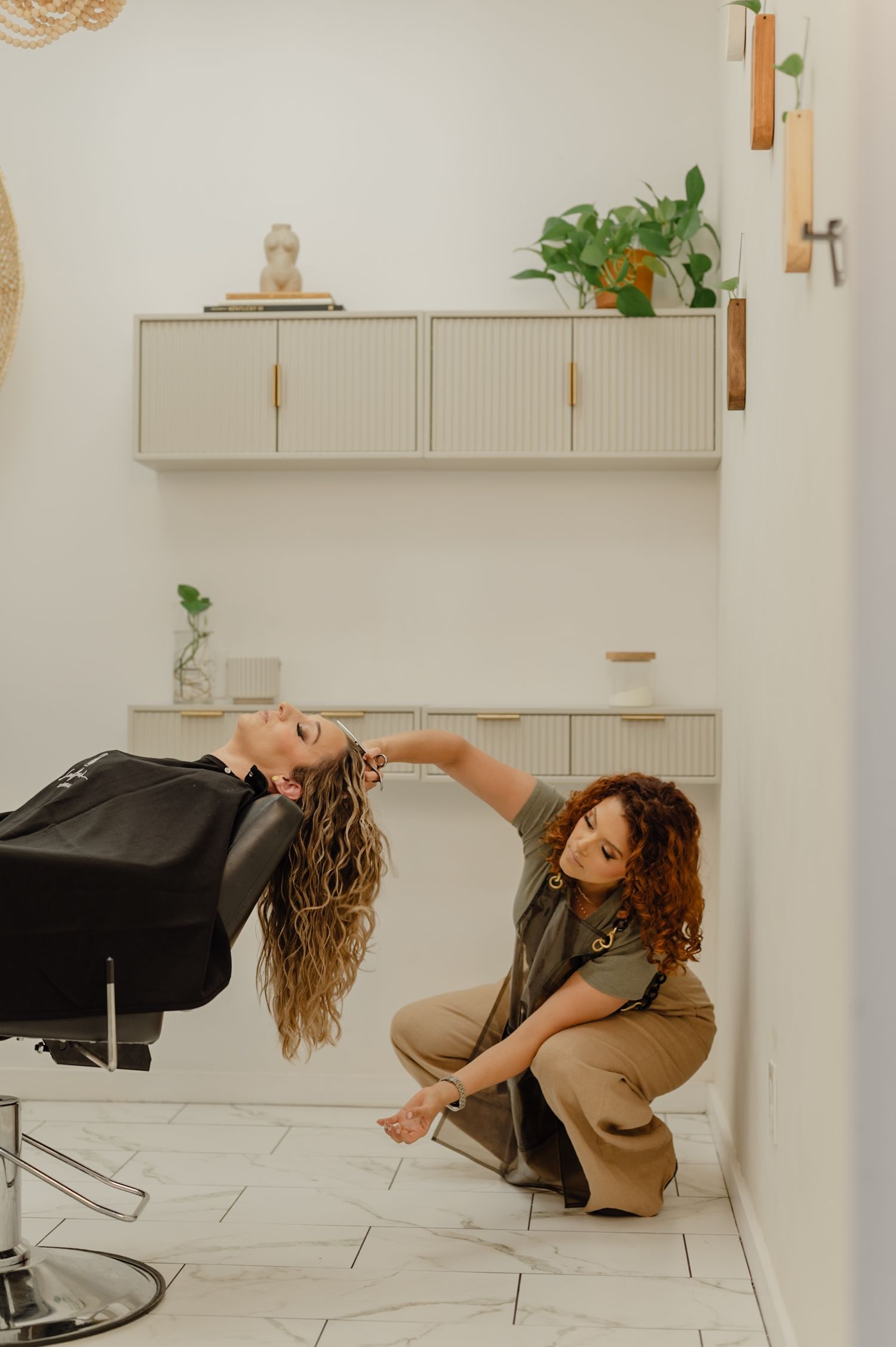 Serena Beach rinses curly hair at Salon Blissful—nurturing curl care in a serene, modern space.