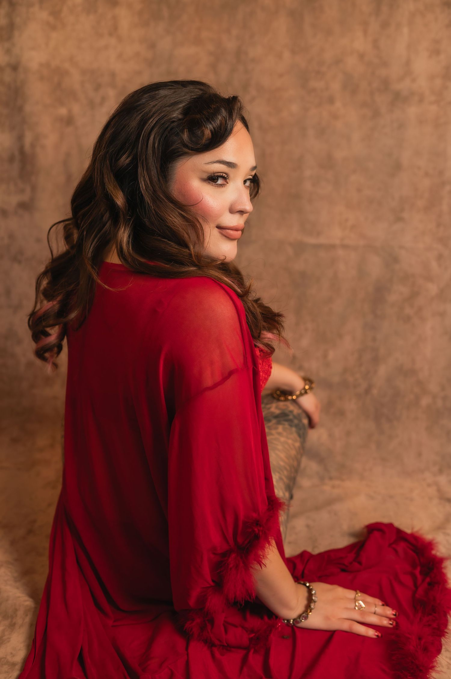Over-the-shoulder portrait of a woman in a red robe with soft curls — from The Hive Salon shoot.