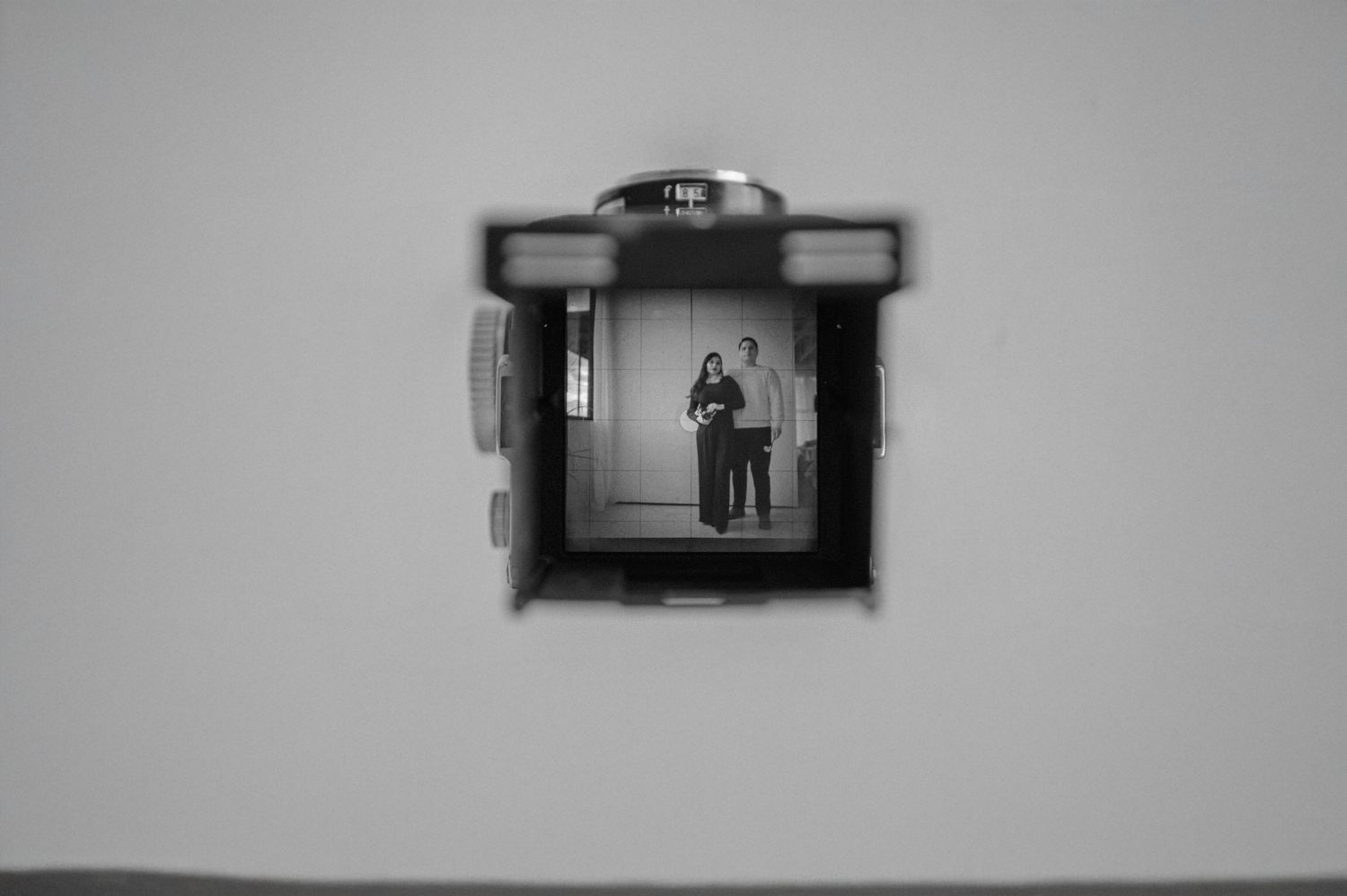 Black-and-white photo of a camera viewfinder framing a portrait of two people — creative branding composition.
