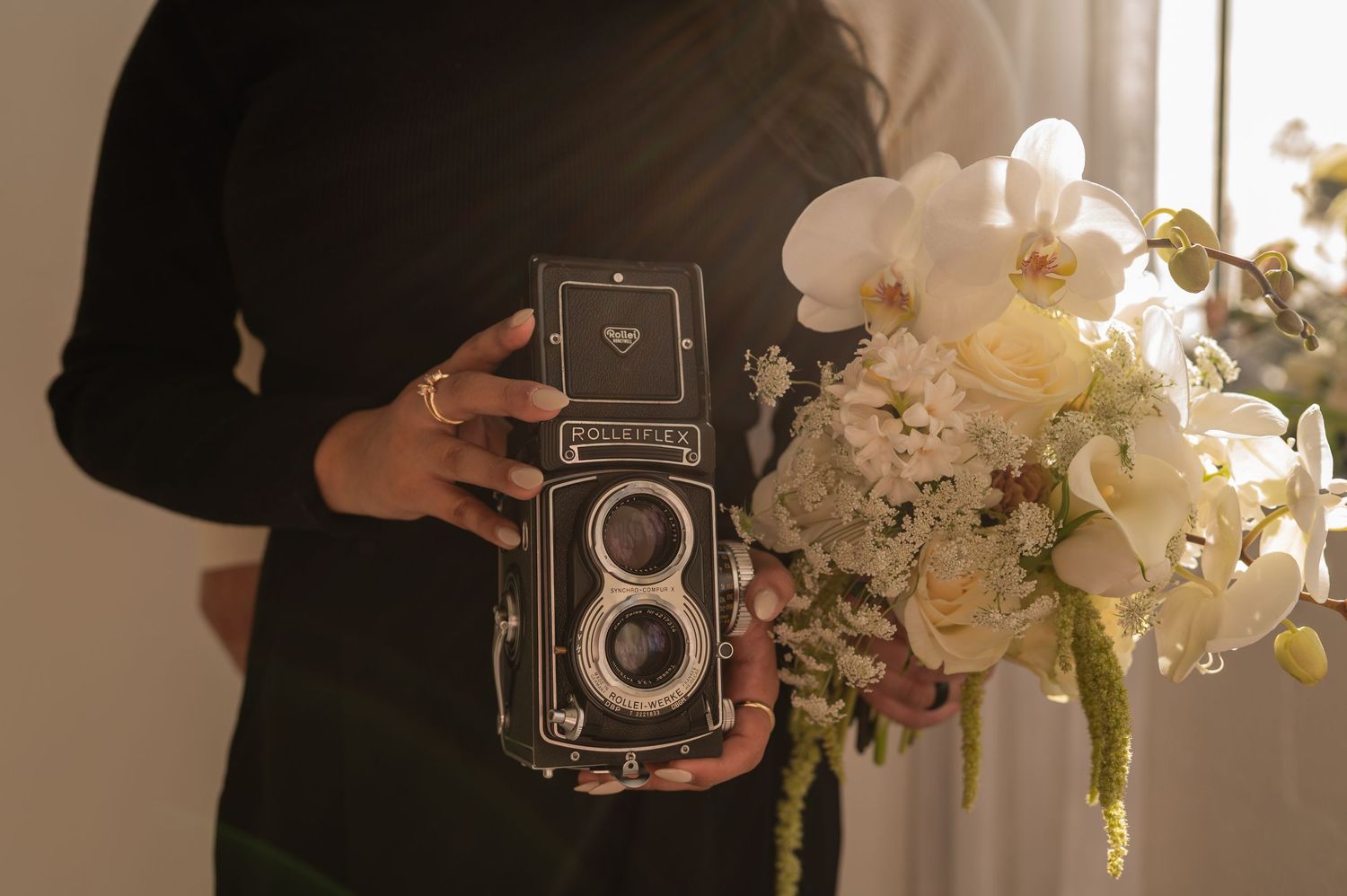 Close-up of a vintage medium-format camera with fresh florals — artistic flat lay representing brand identity.