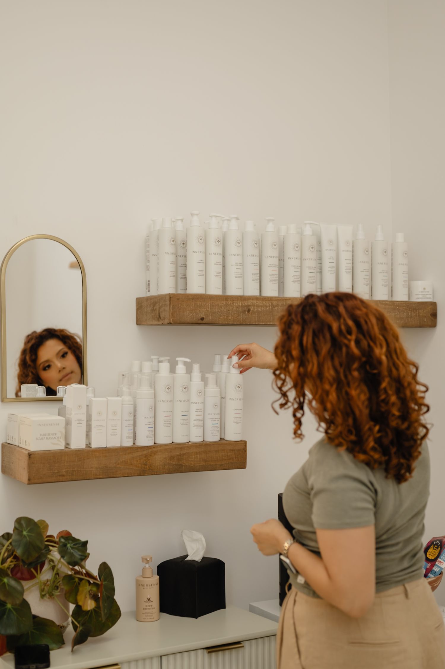 Curly hair product shelf and mirror reflection—Serena Beach curl care suite inside Salon Blissful’s clean modern salon.