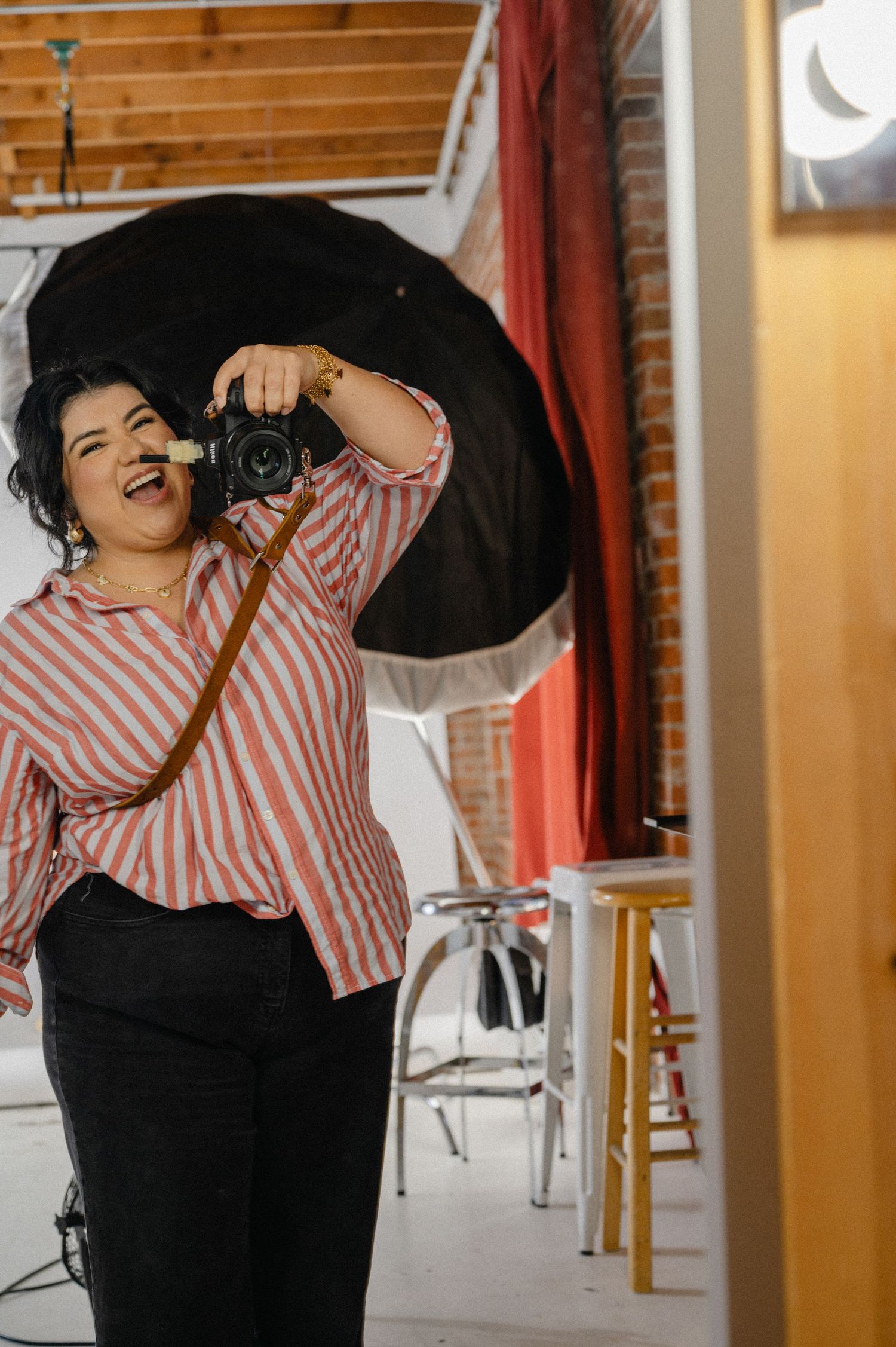 Sharom Rosas, founder of Shamari Visuals, taking a mirror selfie with her camera in her photography studio.