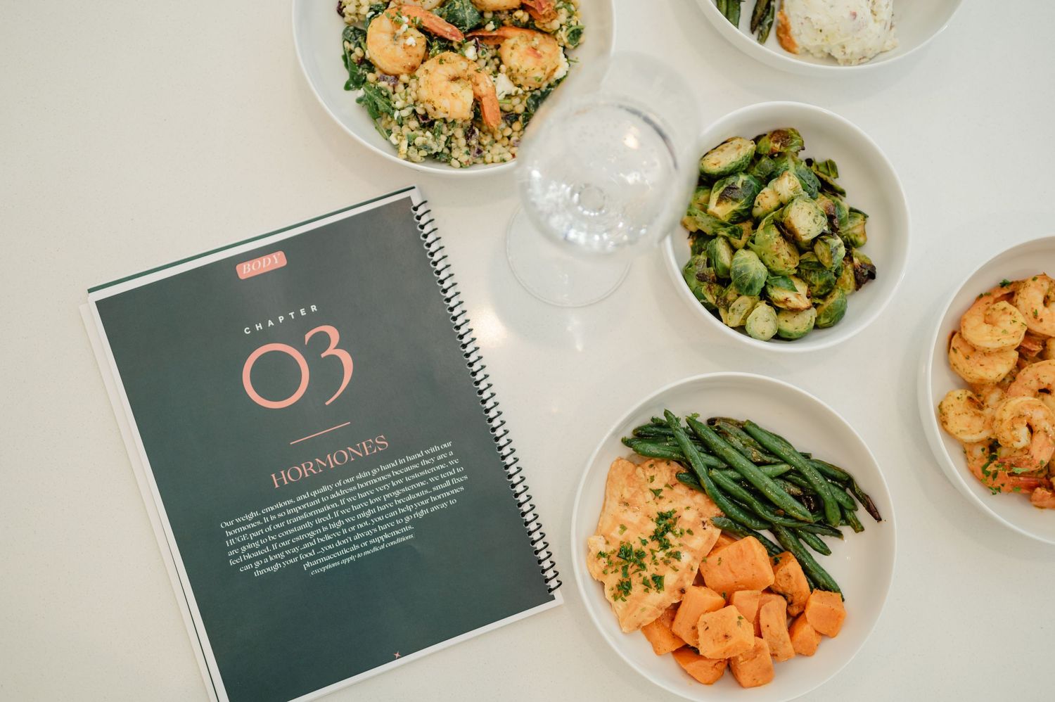 Overhead shot of a meal plan booklet surrounded by prepped meals in glass containers — structured and organized nutrition.