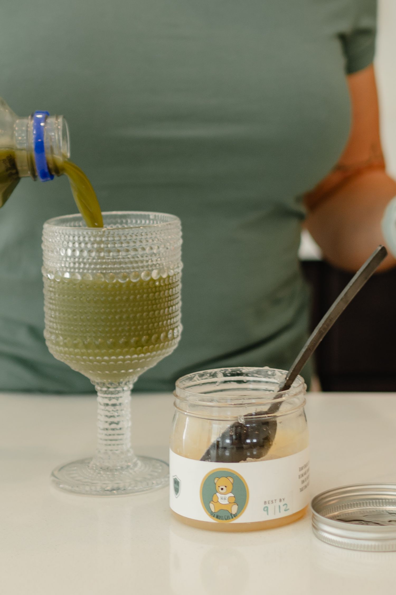 A close-up of a glass of green wellness drink and a branded container — product and lifestyle aesthetic.