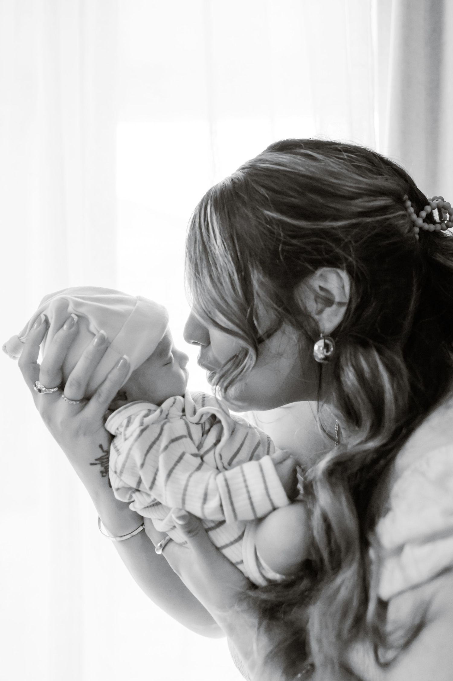 black and white photo of mom nose to nose with her newborn in a striped swaddle, in-home newborn session in phoenix