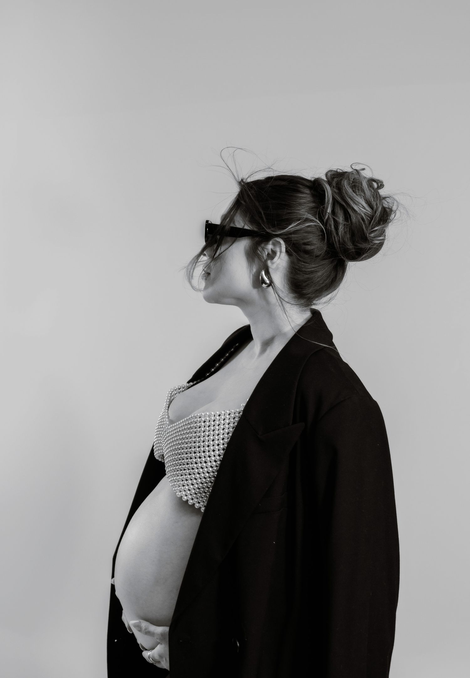 pregnant woman in sunglasses and a black robe cradles her bump during a phoenix editorial session