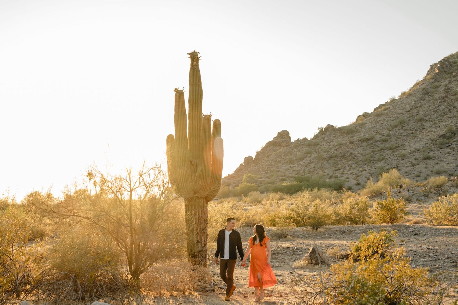 expecting couple walks together near a giant saguaro during a phoenix desert maternity session