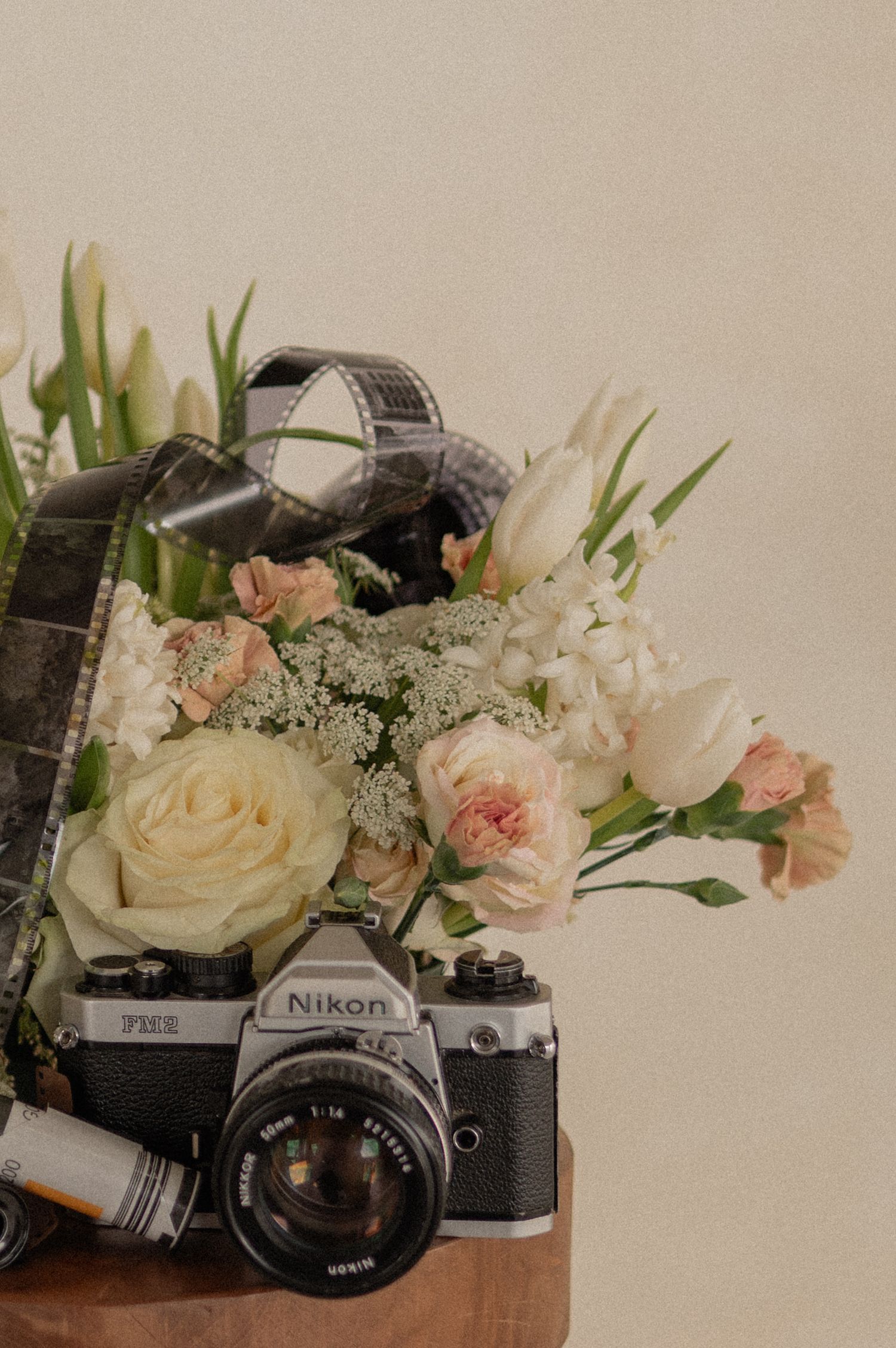 Close-up of a vintage camera surrounded by white and blush florals — warm, romantic still life.
