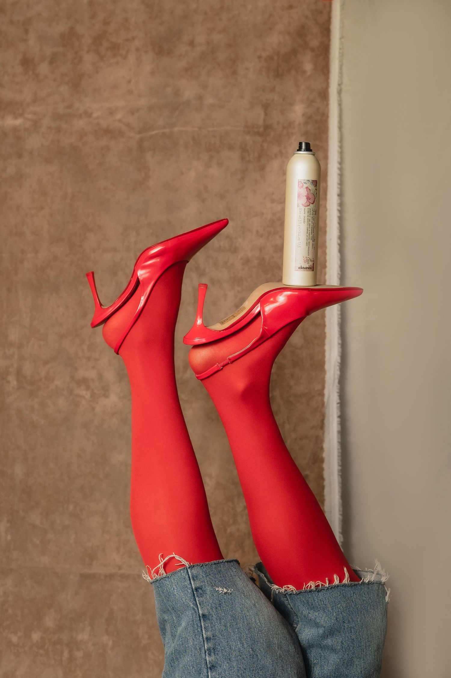 Bright red heels and tights against a neutral wall; a playful pop of color — captured at The Hive Salon.